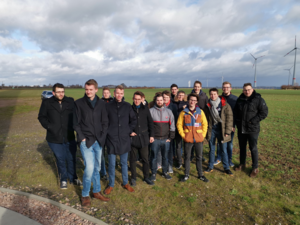 DHBW-Mannheim-Studierende auf einem Feld mit Windrädern der Firma juwi in Wörrtstadt.