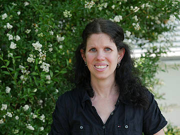 Portrait Prof. Dr.-Ing. Sarah Staub vor einem weiß blühenden Busch auf dem DHBW-Campus Coblitzallee