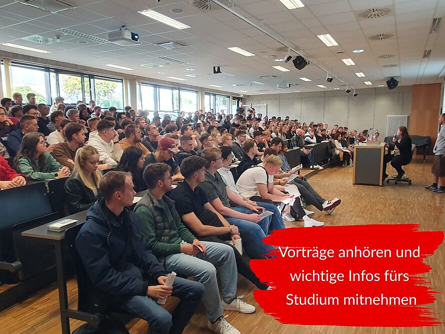 Zahlreiche Erstsemesterstudenten sitzen in einem Hörsaal und verfolgen einen Vortrag. Text lautet: „Vorträge anhören und wichtige Infos fürs Studium mitnehmen.“