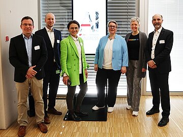Gruppenfoto mit 6 Menschen vor einem Bildschirm mit dem Schriftzug zum DHBW AI Transfer Congress