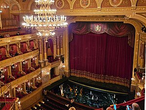 Blick von der Empore auf den geschlossenen roten Vorhang der Bühne in der Staatsoper.