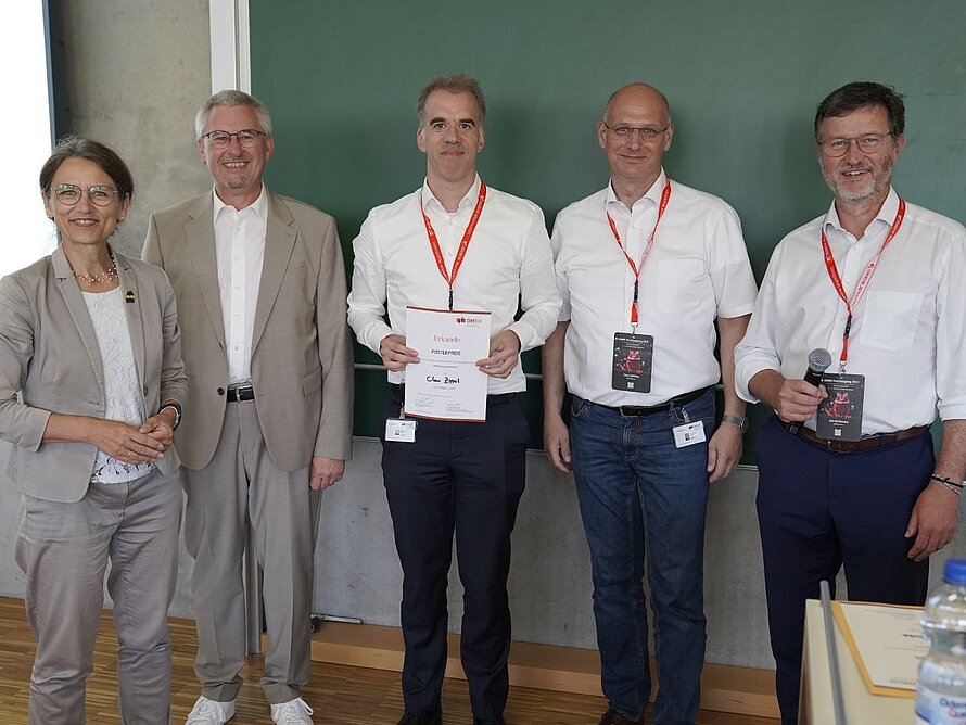 Gruppenbild mit 5 Personen, ein Mann in der Mitte hält eine Urkunde.  