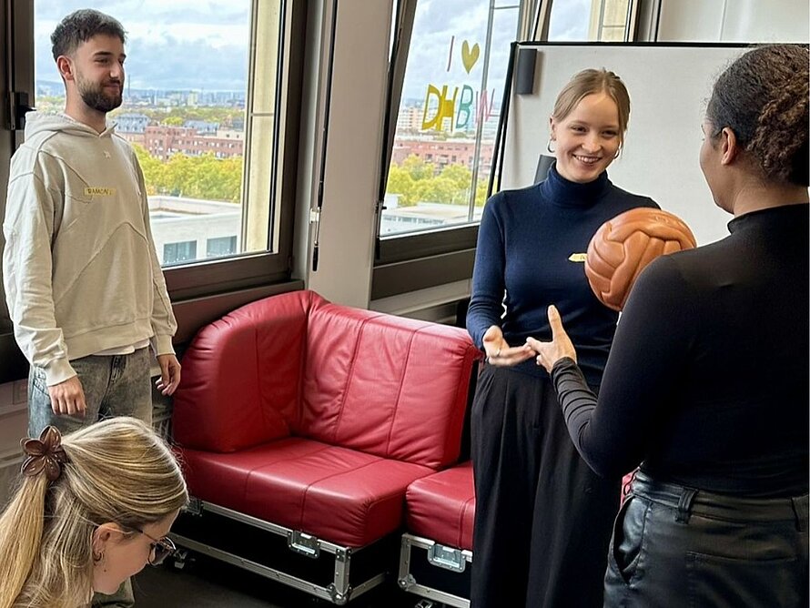 Studierende interagieren spielerisch mit einem ledernen alten Ball im Design Thinking Labor.