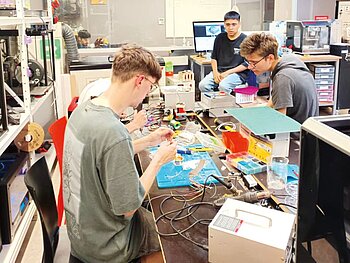 Die drei deutschen Studierenden zusammen mit einem chilenischen im Labor der UDD, wo sie die Teile des Luftqualitätssensors verlöten. 