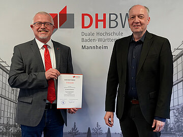 Zwei Männer in Anzug von einem schwarz-weißen Bild des Campus der DHBW Mannheim 