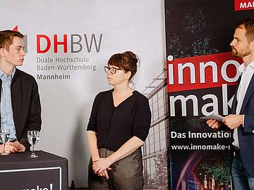3 Personen vor den Roll-ups der DHBW-Mannheim und des innomake Festivals