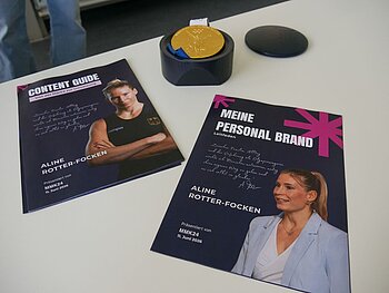 Zwei dunkelblaue Heftchen mit Aline Rotter-Focken abgebildet liegen auf dem Tisch