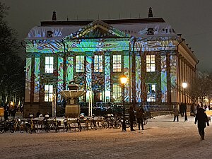 Lila und türkis beleuchtetes altes verschneites Gebäude.