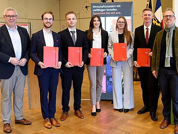 Gruppenfoto mit 5 Studierenden, die eine rote Urkundenmappe in der Hand halten, links und rechts daneben die beiden Bürgermeister der Stadt Mannheim. 