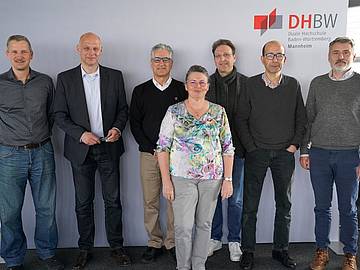 Gruppenbild Vor DHBW-Hintergrund Sechs Männer im Hemd und eine Frau im Vordergrund