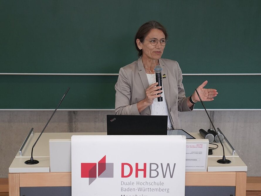 Frau an einem Pult mit dem DHBW-Mannheim-Logo spricht zum Plenum
