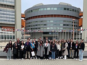 Gruppenfoto mit Studierenden vor einem runden Gebäude der Vereinten Nationen.