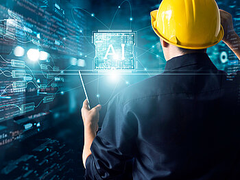 Ein Mann mit gelbem Schutzhelm steht mit dem Rücken zur Kamera und blickt auf eine leuchtendes KI-Chip-Symbol, umgeben von vernetzten Datenknoten, Schaltplänen und Begriffen wie „Factory“, „Security“ und „Production“. Die Szene ist in technischem Blau gehalten und symbolisiert die Integration von Künstlicher Intelligenz in die moderne Industrie.