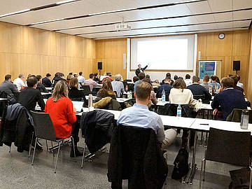 Teilnehmende an einem Workshop von hinten an Tischreihen sitzend, vorne an einem Whiteboard spricht Prof. Dr. Harald Kornmayer der DHBW Mannheim.