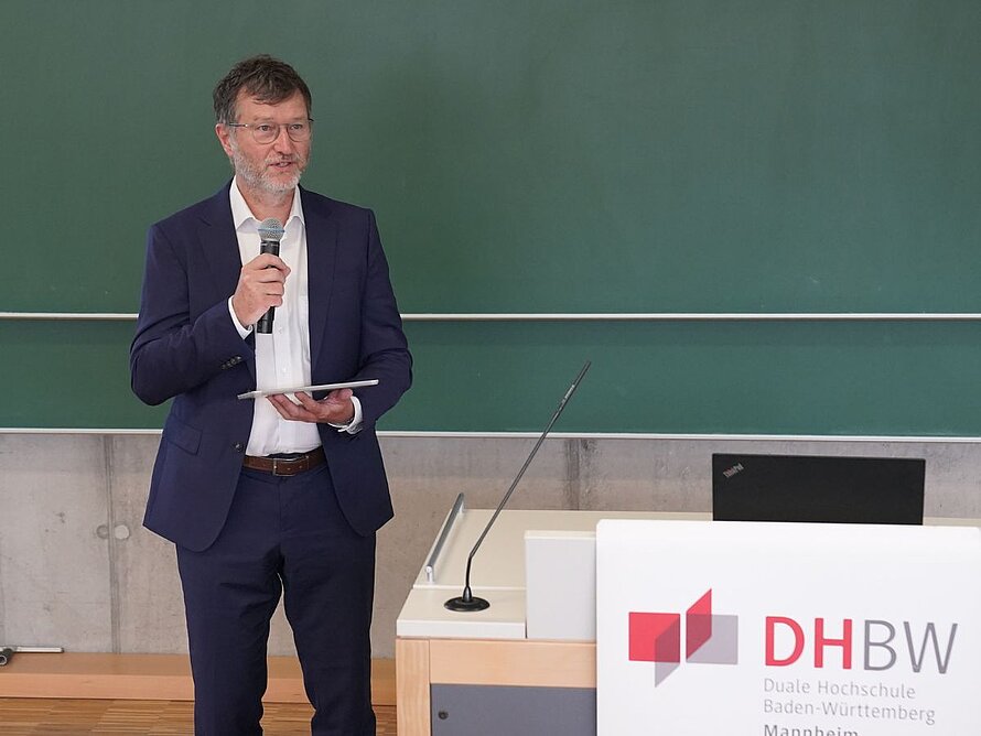 Mann mit Mikrofon spricht zu Plenum