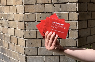 Gutscheinbuch der Stadt Mannheim Hand hält vor einer Steinwand das Gutscheinbuch der Stadt Mannheim, das sich Erstsemester umsonst abholen dürfen