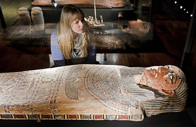 Reiss-Engelhorn-Museen: Ausstellung „Ägypten – Land der Unsterblichkeit“ Blick in die Ausstellung „Ägypten – Land der Unsterblichkeit“ der Reiss-Engelhorn-Museen: Eine blonde junge Frau betrachtet eine in einer Vitrine liegende ägyptische Figur