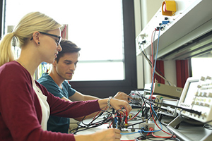 Eine Studentin und ein Student bedienen ein Messgerät der Elektrotechnik