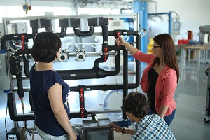 Zwei Studentinnen und ein Student (von hinten gesehen) bedienen den Teststand Wärmeüberträger im Labor Thermische Verfahrenstechnik der DHBW Mannheim 