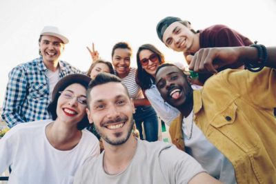 8 junge Erwachsene unterschiedlicher Geschlechter und Hintergründe lachen in die Kamera, eine Person davon zeigt mit den Händen ein Victory-Zeichen. 