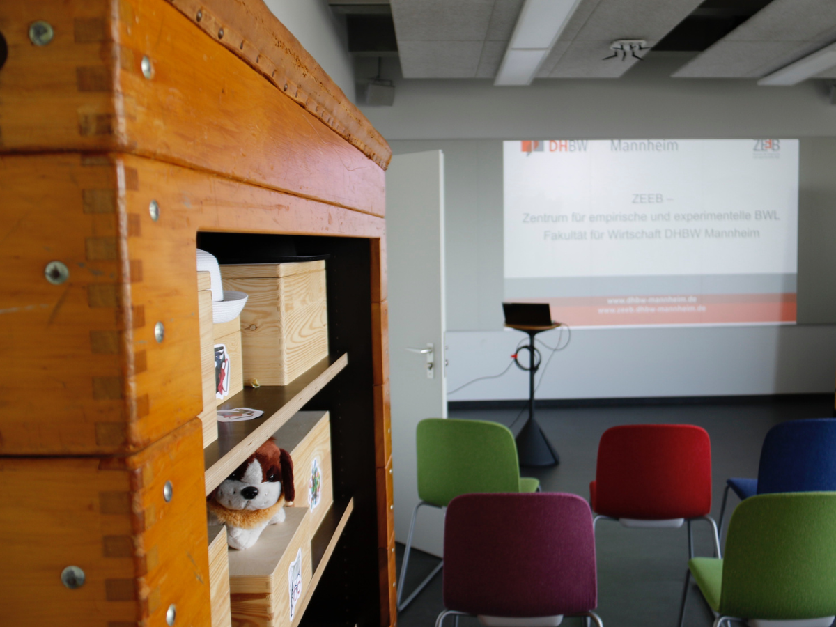 Blick von hinten auf die Leinwand und bunte Stühle im größten Raum des Design Thinking Lab.